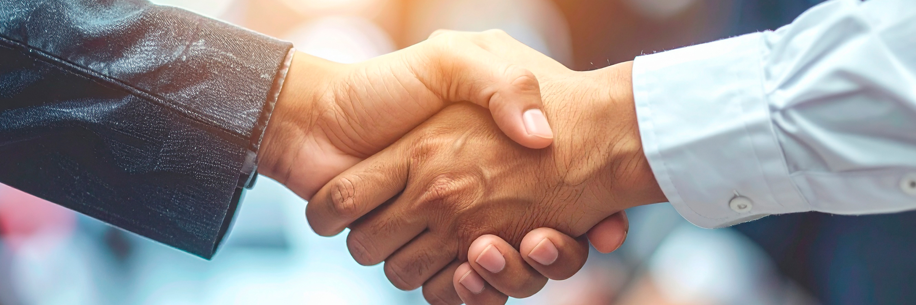 A close-up of a professional handshake taking place over documents in a business meeting, symbolizing a trusted partnership and agreement.