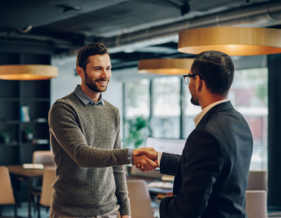 Sales professional shaking hands with a quality manager in a laboratory, representing partnership and accessible testing services.